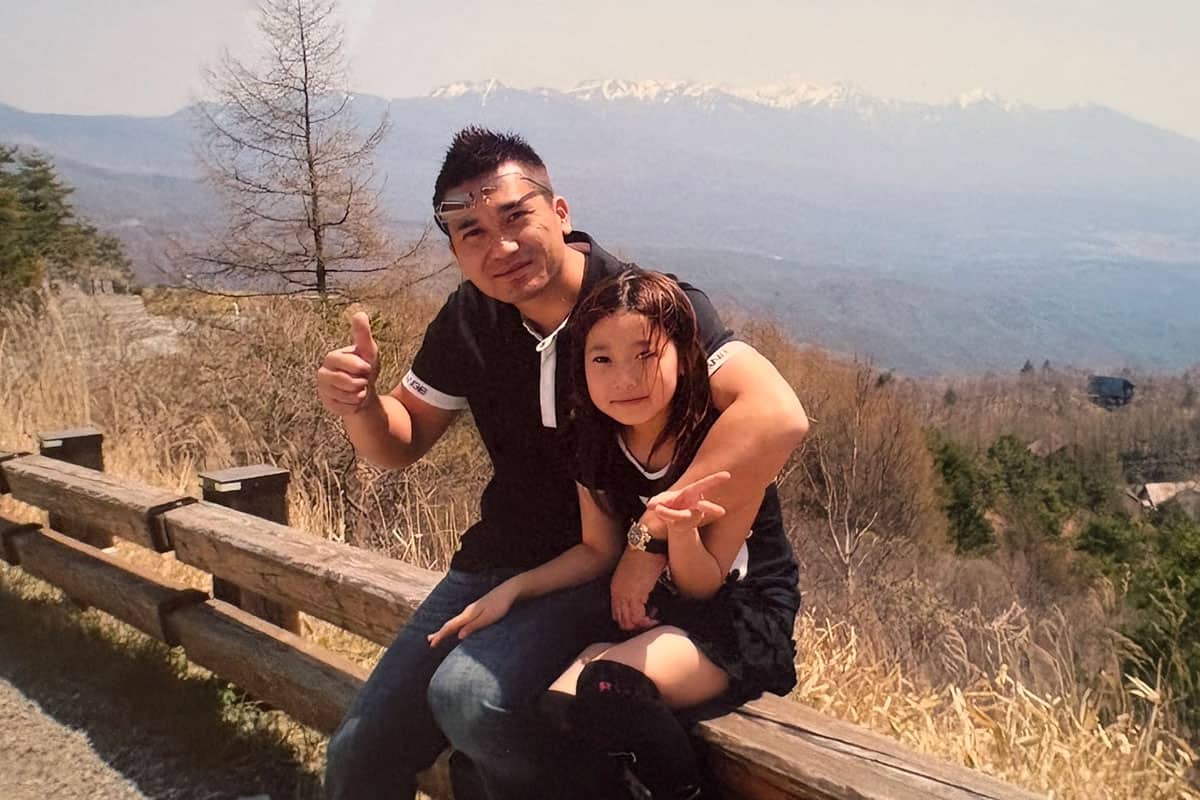 家族旅行で温泉へ行き、雄大な景色をバックにポーズを取る父と芽依。父がお風呂好きなためか、家族旅行は温泉が多かったという
