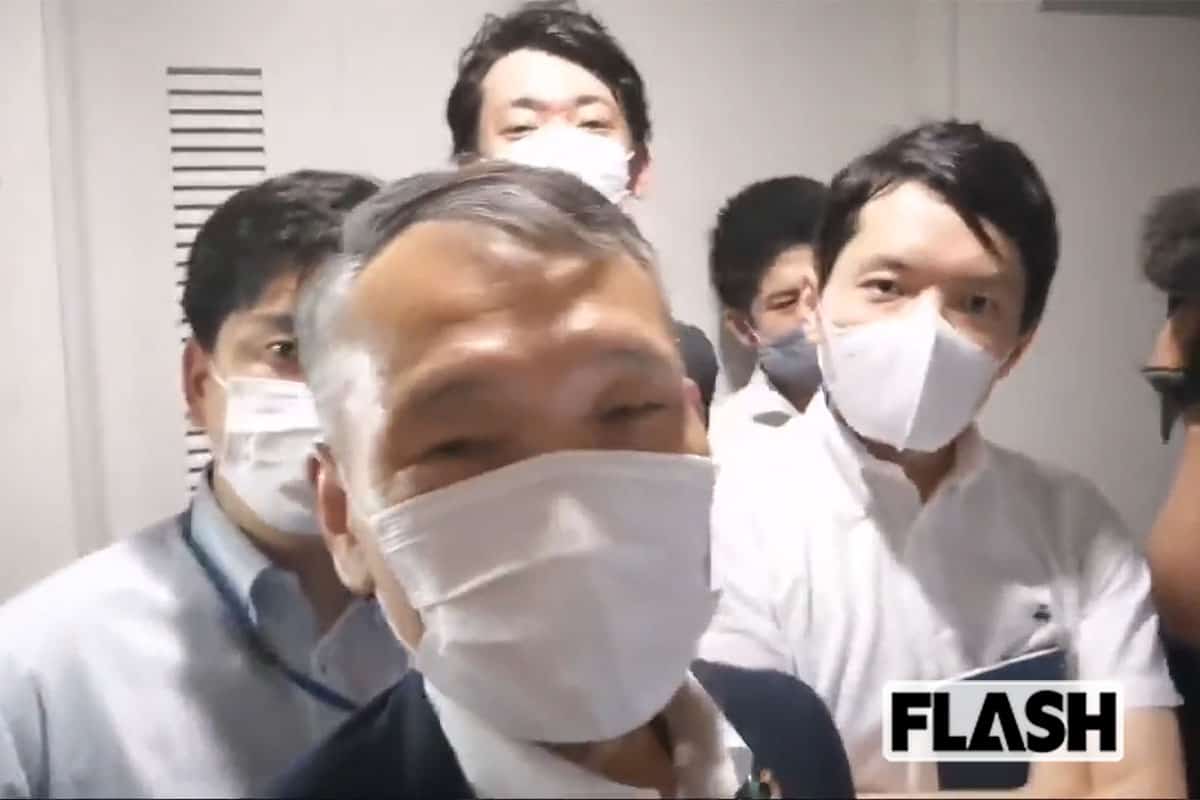 会見会場に入ろうとする筆者らの前に立ちふさがる共同通信社の前田晋吾鹿児島支局長(当時。中央のジャケット姿の男性)、久納宏之記者(右、ノートを持った男性)