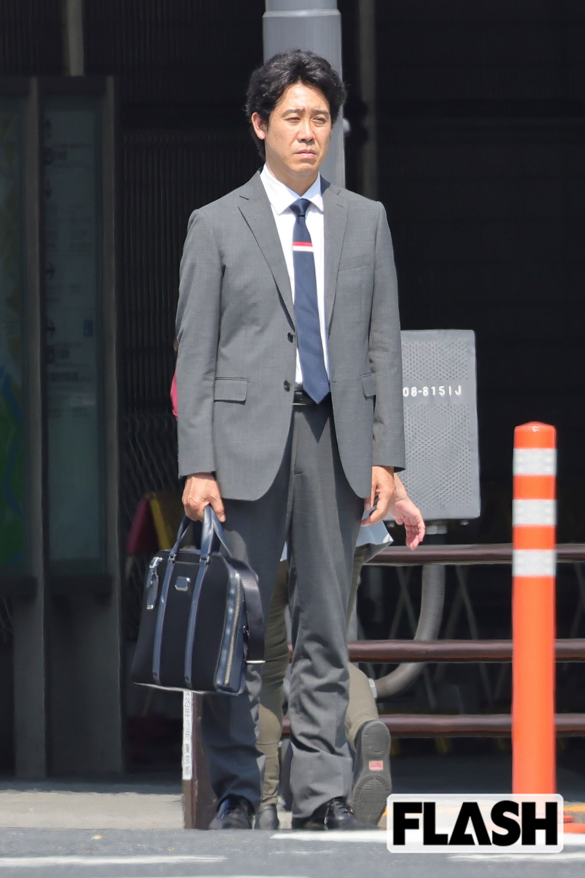 グレーのスーツを着たまま路上に立ち尽くす大泉洋