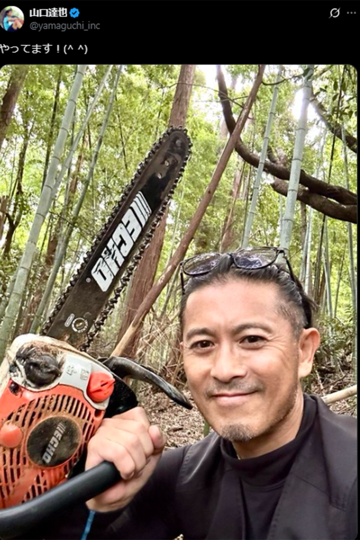 森のなかでチェーンソーを持つ山口達也（10月17日投稿の山口のX「@yamaguchi_inc」より）