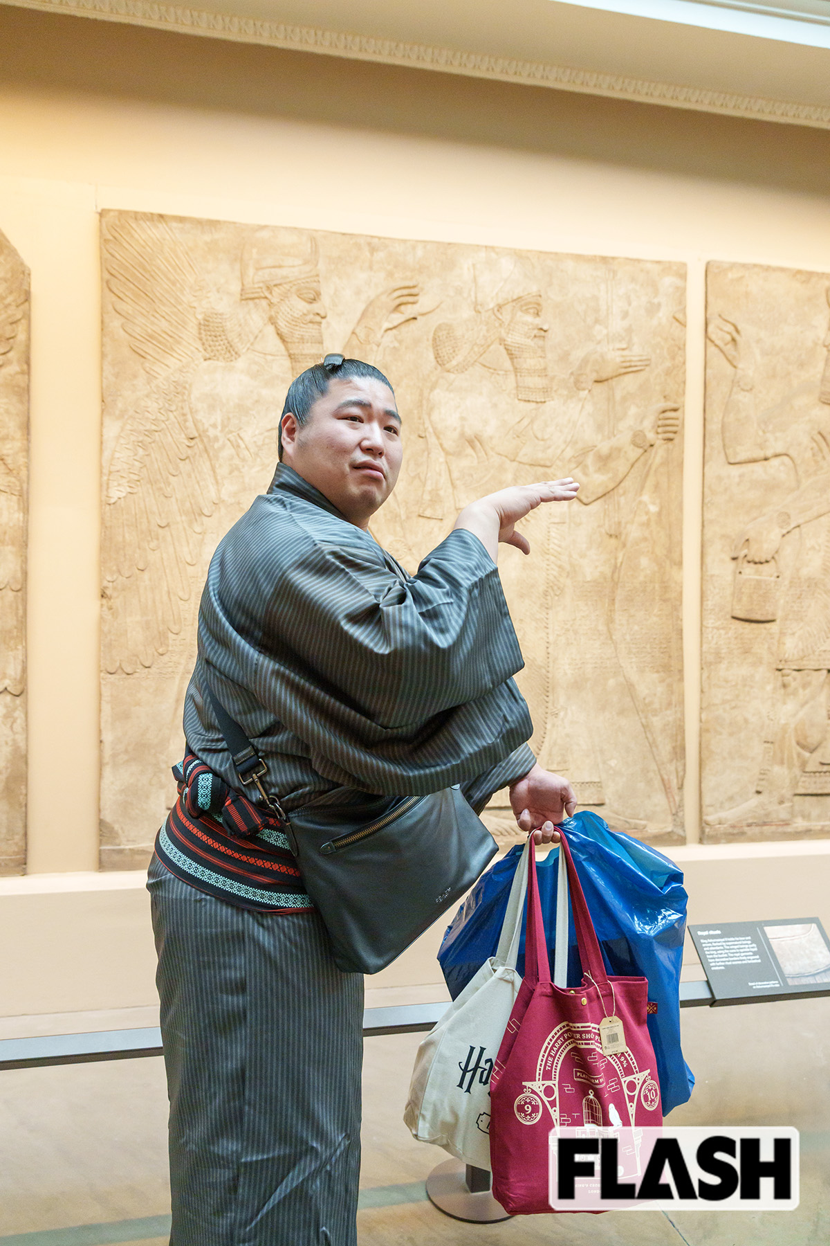 ハリポタグッズの詰まった袋を片手に、大英博物館のアッシリア時代の壁彫刻の前でポーズを取る若元春(写真・高橋マナミ)