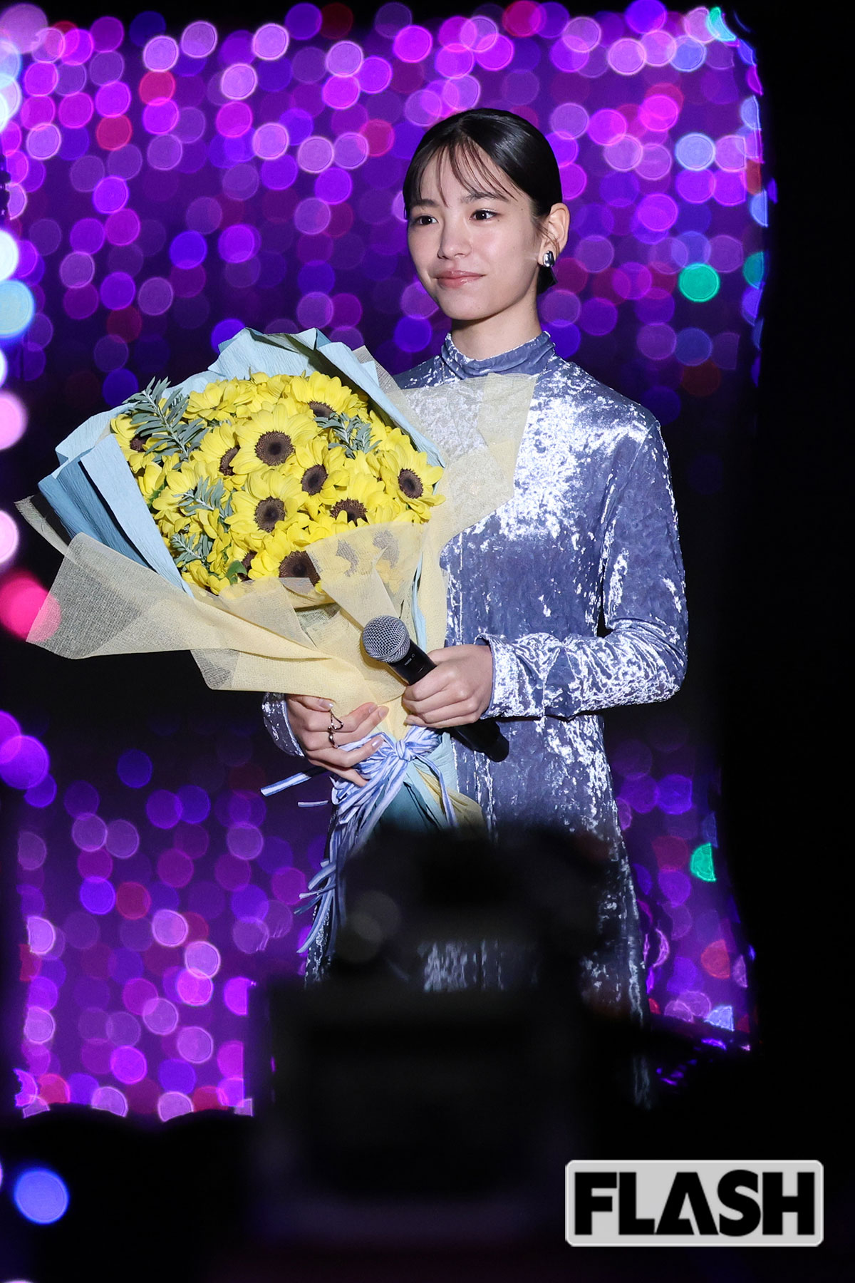 ひまわりの花束を片手に笑顔を見せる當真あみ