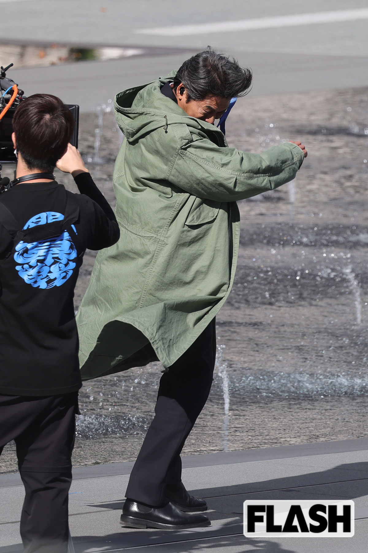 風の強さに思わず顔を隠す織田裕二