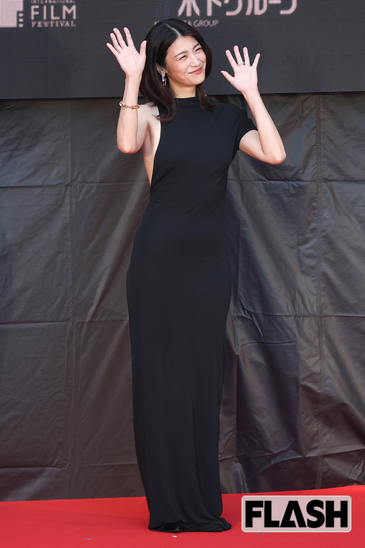 笑顔で手をふる瀧内公美。大胆にサイドにカットの入ったドレスだ