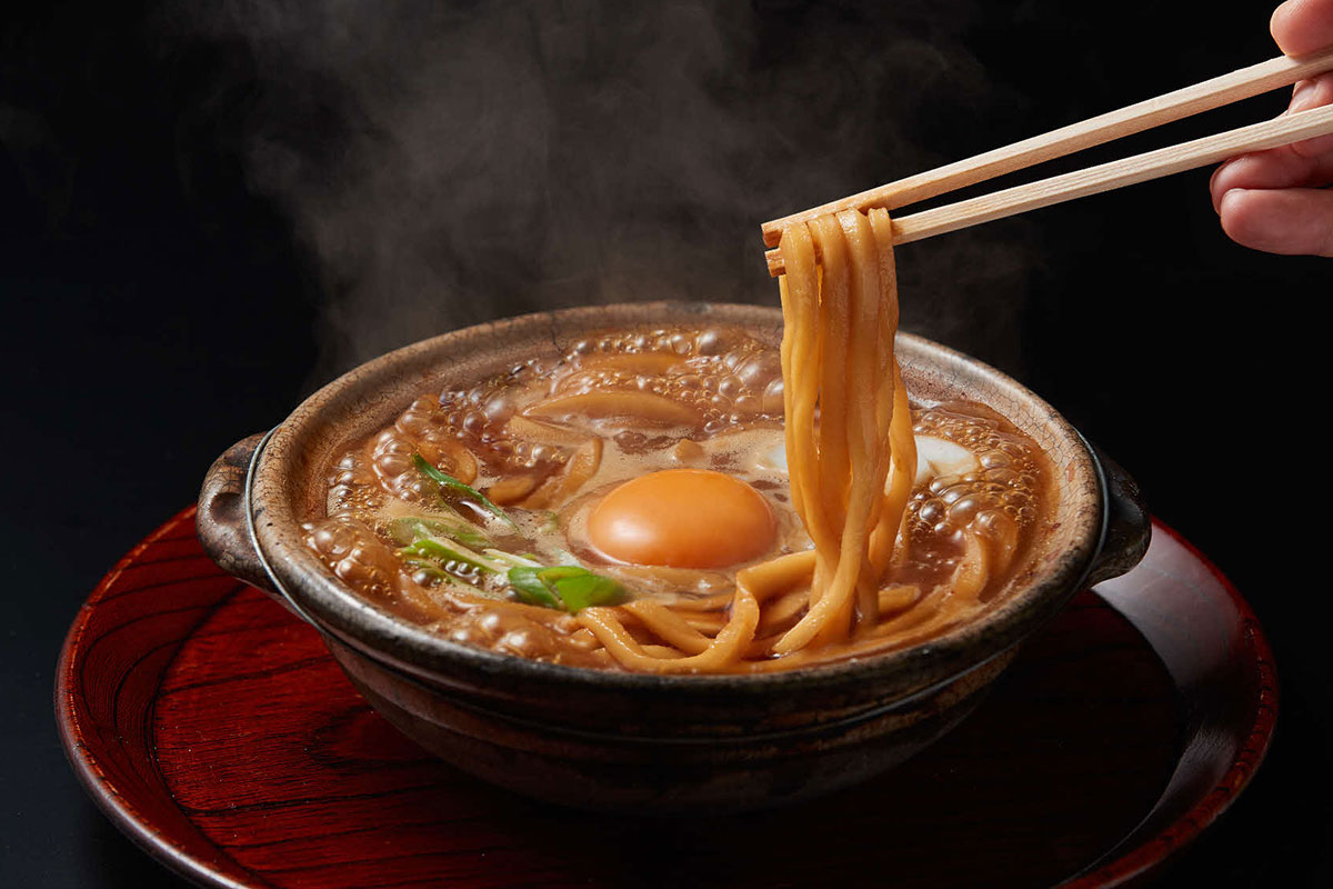 【山本屋本店】JR名古屋駅名古屋うまいもん通り　広小路口・営業時間／11:00～22:00（L.O. 21:30）年中無休。麺をしっかり噛んで赤味噌と一緒に味わうおいしさが山本屋本店の魅力。赤味噌に鰹出汁がきいたスープ、噛み応えのある麺は、一度体験する価値あり。JR在来線の広小路口改札に近く、電車の発車時刻ぎりぎりまで食事を楽しめる。