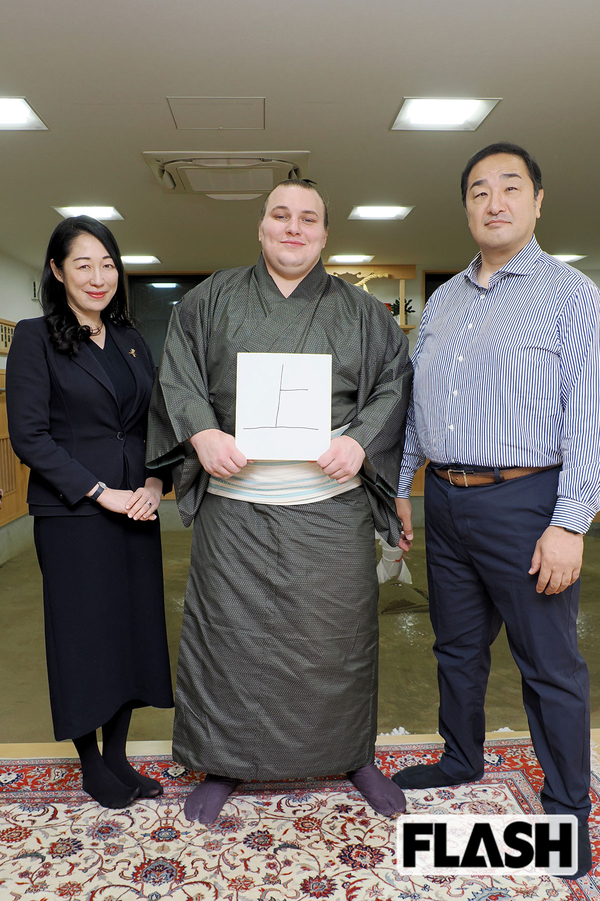 おかみさんの杉野森絵莉さん（左）、安青錦関（中央）、安治川親方と。安青錦関が色紙に直筆で書いた「上」の文字には「さらに上を目指す」という思いがこめられている（写真・梅基展央）