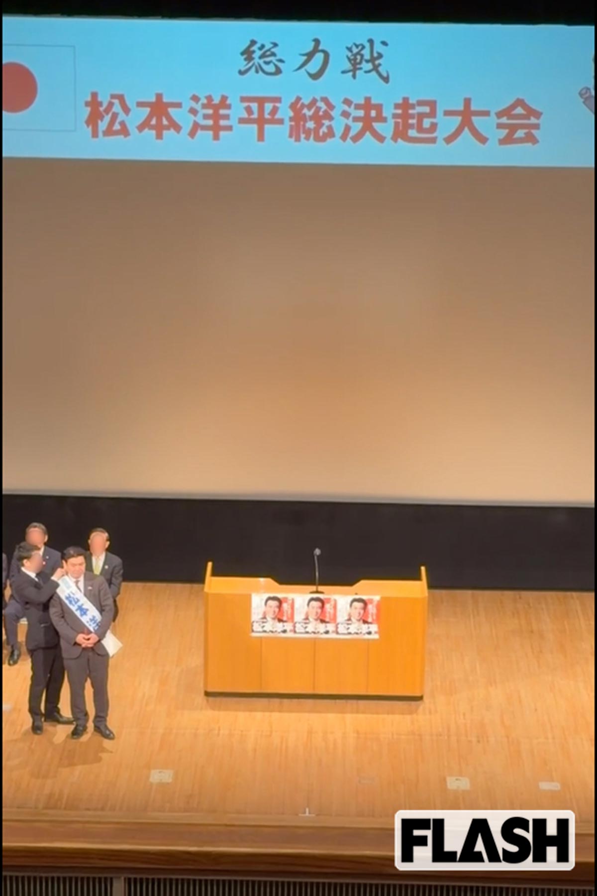 「総力戦　松本洋平総決起大会」と会の名称が映し出された檀上