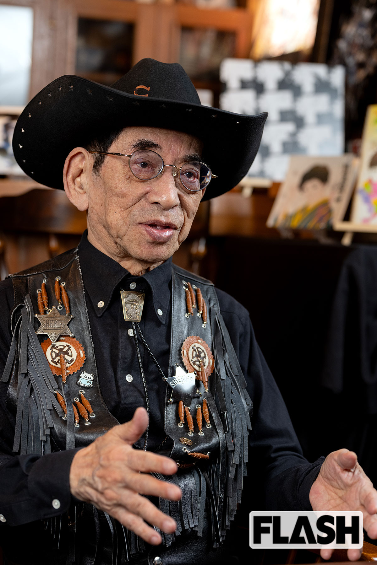 数々のレジェンドと交友のあるバロン吉元氏。バロン・プロの応接間の壁には、作品がびっしり掛けられている。「これはね、宇宙人の骸骨なんですよ」。完全未発表の作品群は、今後展示も考えているという（写真・福田ヨシツグ）