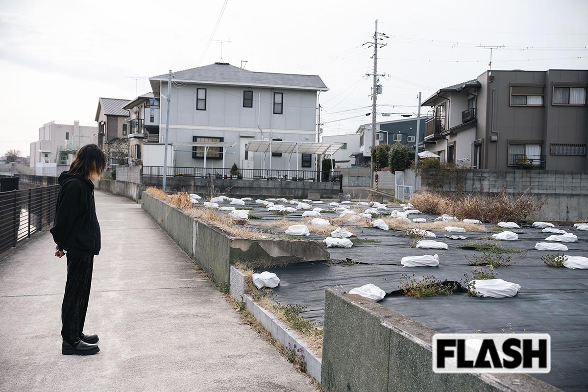 自宅の跡地に立つ林氏（長男）。2000年に放火のため全焼したが、壁の落書きを消した跡がいまも残る（写真・木村哲夫）