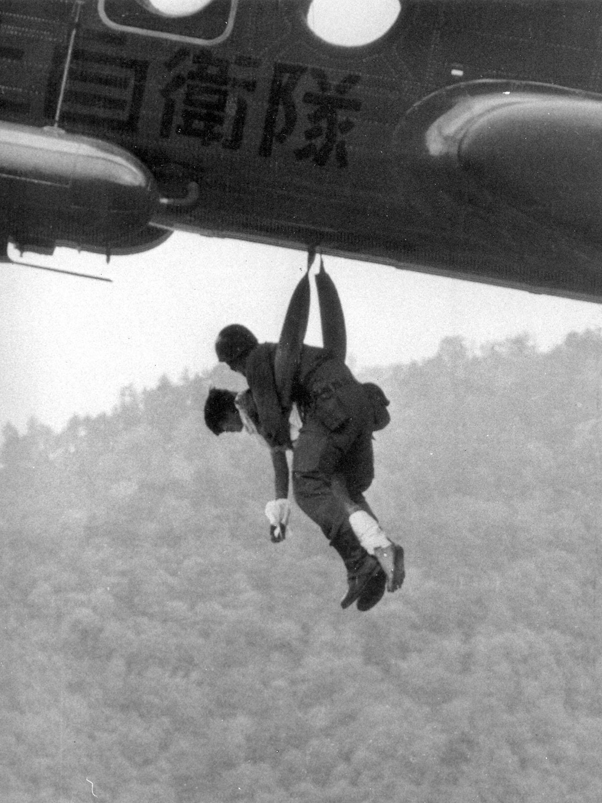 奇跡的に生存し、作間氏によってヘリコプターに吊り上げられる少女。 相田氏は、機体内部にほふく前進しながら入り、彼女に声をかけたと語っている（写真・毎日新聞社／アフロ）