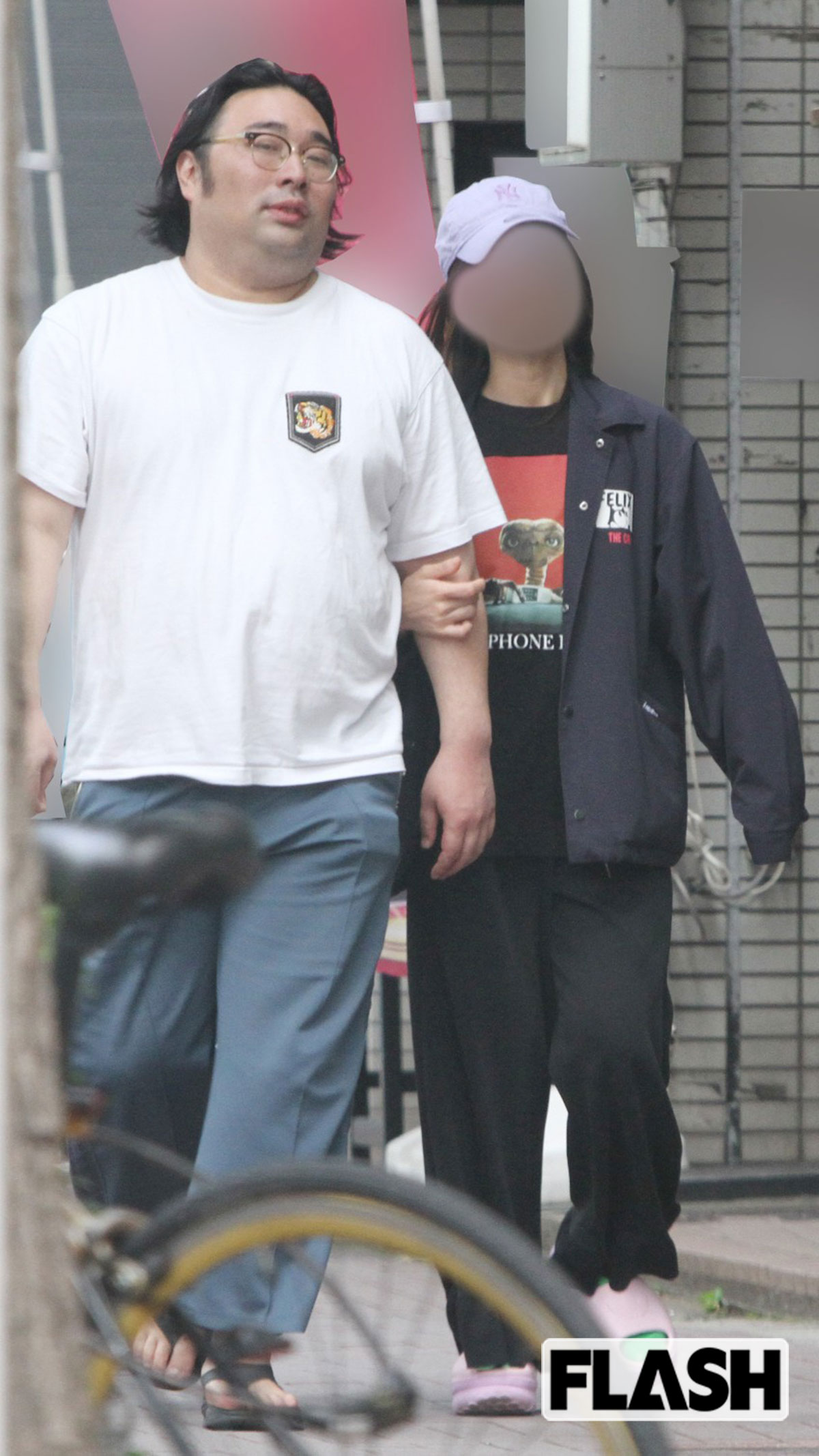 2026年5月、妻のA子さんと一緒にパチンコ店を出たビスケットブラザーズ・原田泰雅。大通りの交差点では人目を気にしてか、数歩離れて信号を待っていたが、人通りが少なくなると、おもむろにA子さんが原田の腕に手を回して、体を寄せ合っていた。寡黙のイメージが強い原田だが、ときおり見つめ合ったり、笑いあったりと幸せそうな様子だ（写真・金谷千治）
