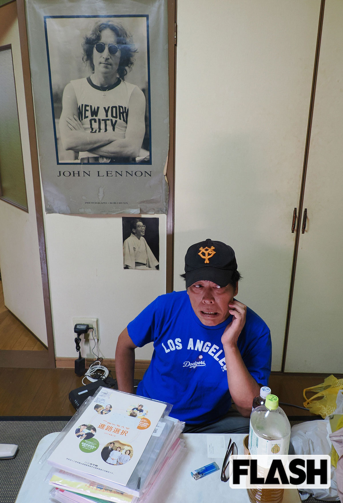 ロックバンドをしていたという小堀の部屋の壁には、ジョン・レノンのポスターと落語家時代の師匠・初代三遊亭圓丈の写真が飾られていた（写真・保坂駱駝）