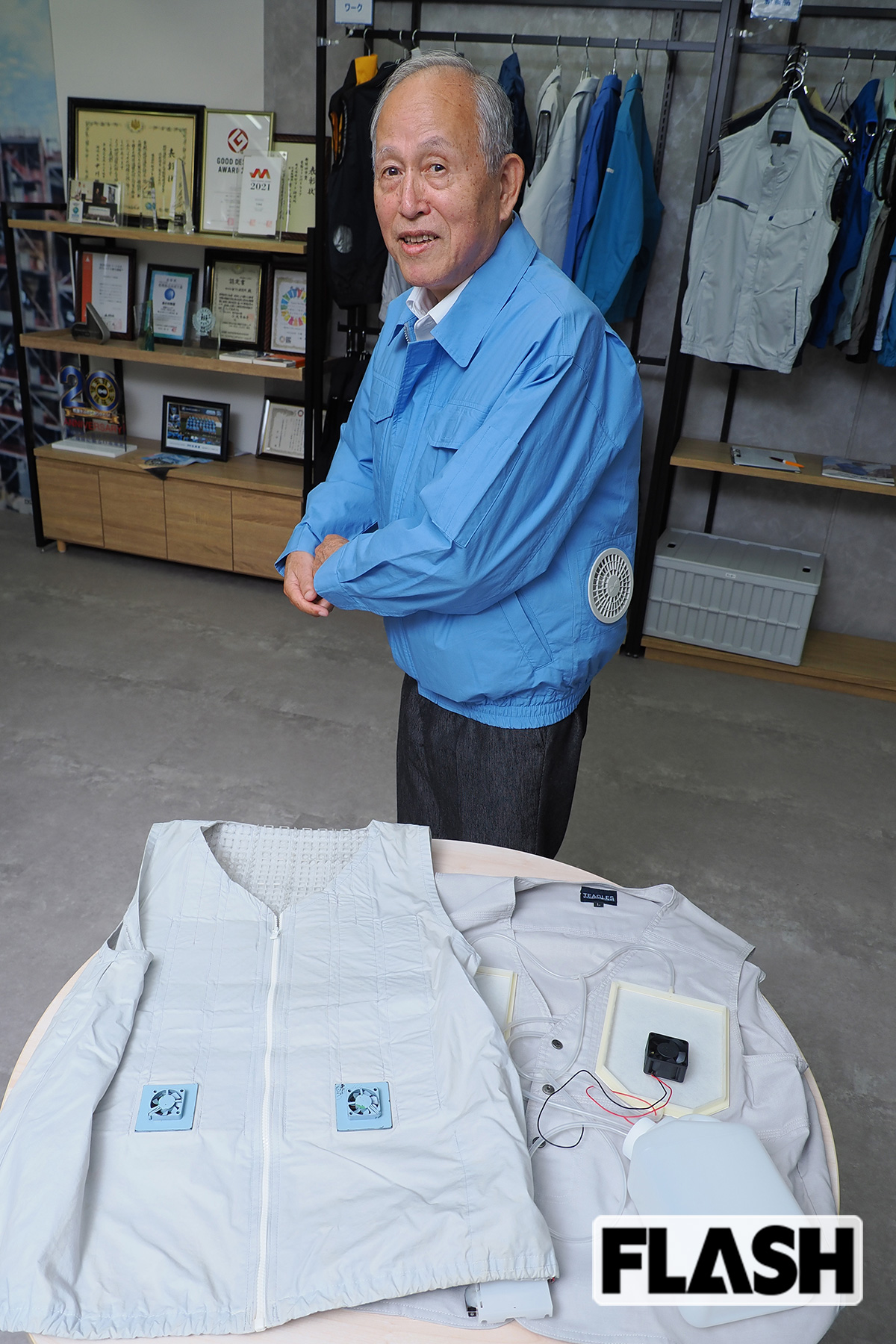 空調服を着る市ヶ谷弘司さん。手前右は、水を使った1999年モデル。左はまだファンが小型だった2001年モデル（写真・梅基展央）