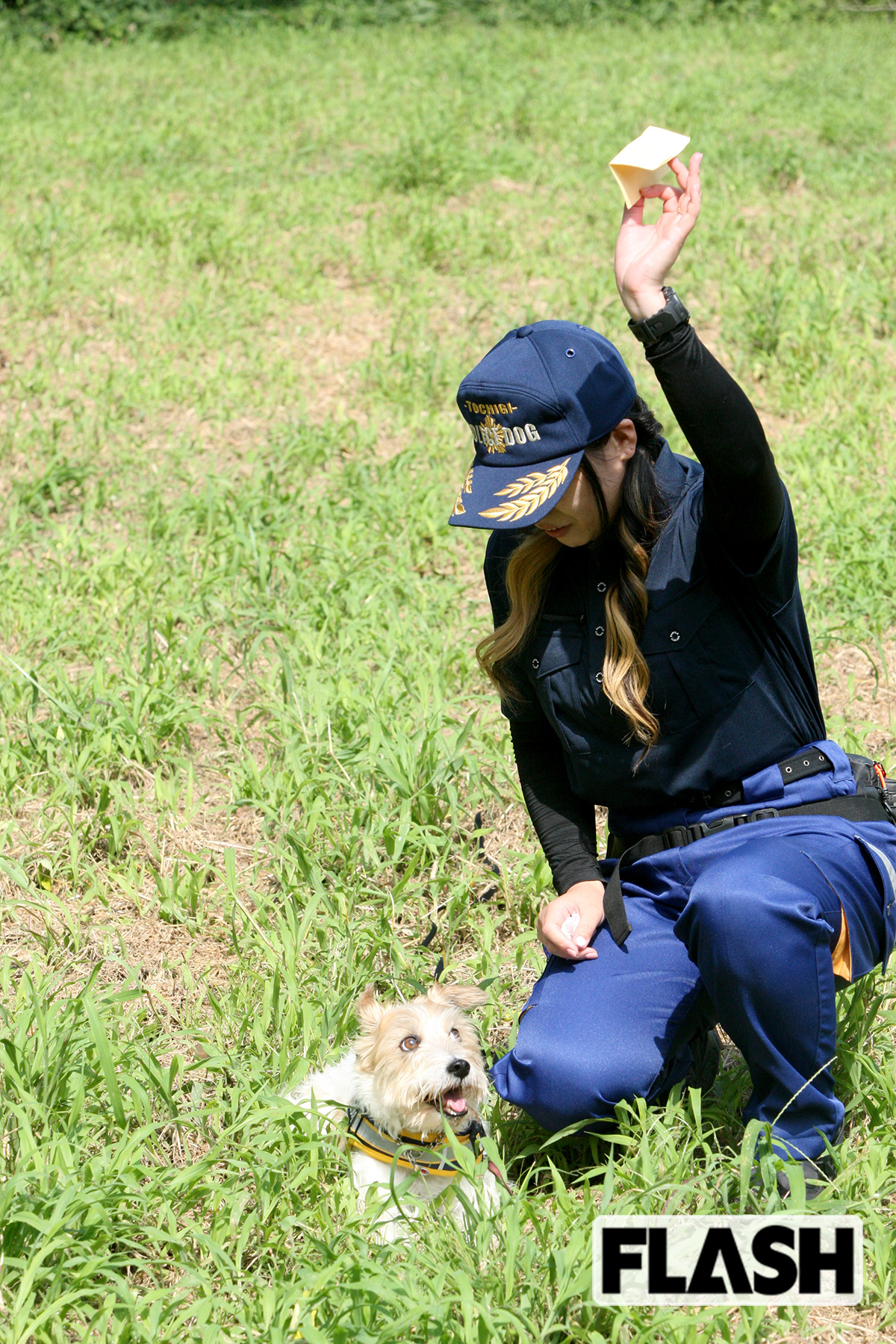 においをつけた紙を草むらから探し当てたカノンと、飼い主で訓練士の飯田早希さん。過去には行方不明者を発見した実績も（写真・保坂駱駝）